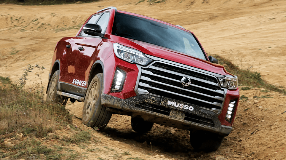 Red 2021 SsangYong Musso driving off-road