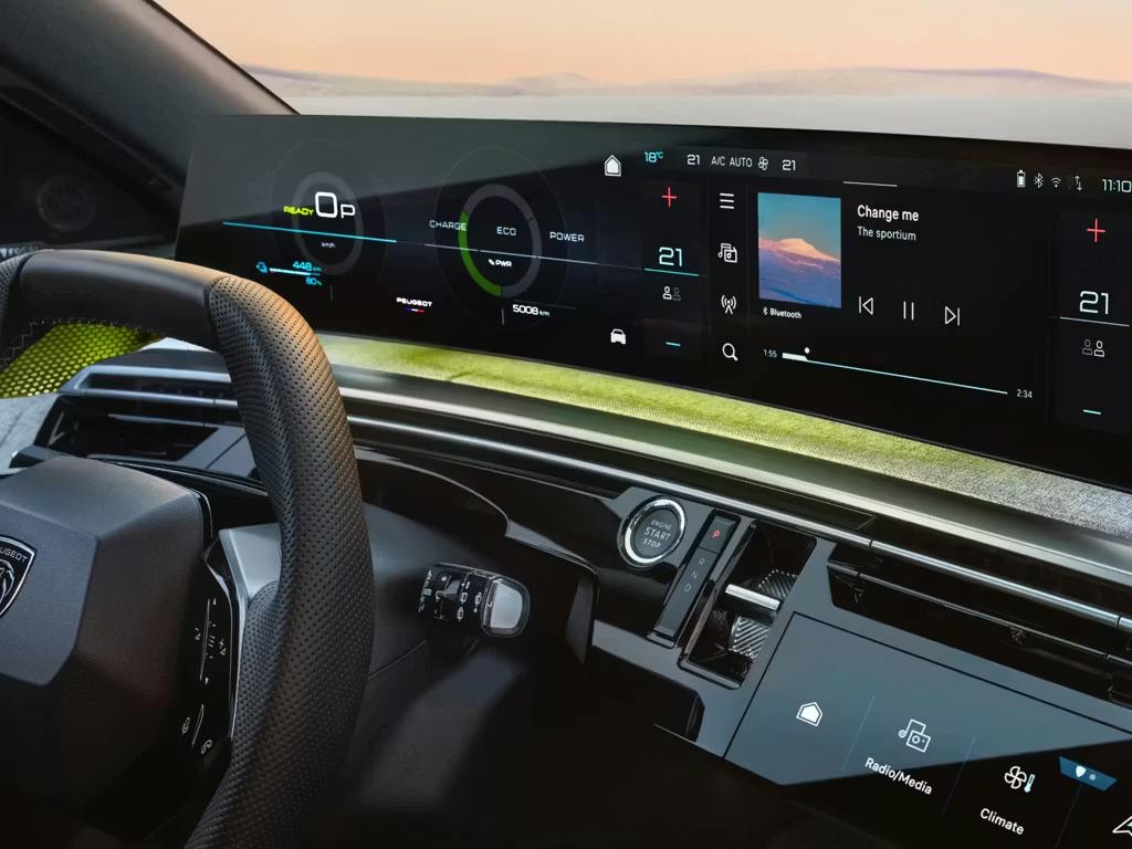 Interior view of the Peugeot 5008, featuring the panoramic i-Cockpit with curved digital instrument cluster, central touchscreen displaying climate and media controls, and compact steering wheel.