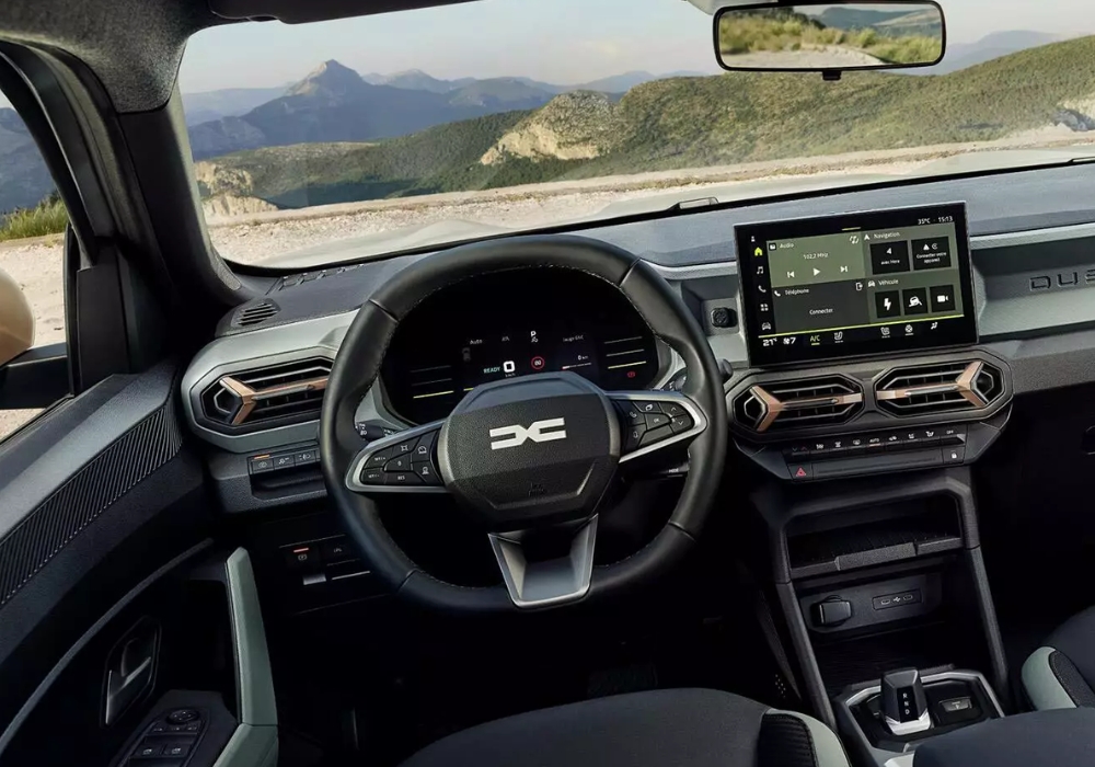 Dacia Duster interior with steering wheel and central touchscreen display, showing dashboard layout with mountain scenery ahead.