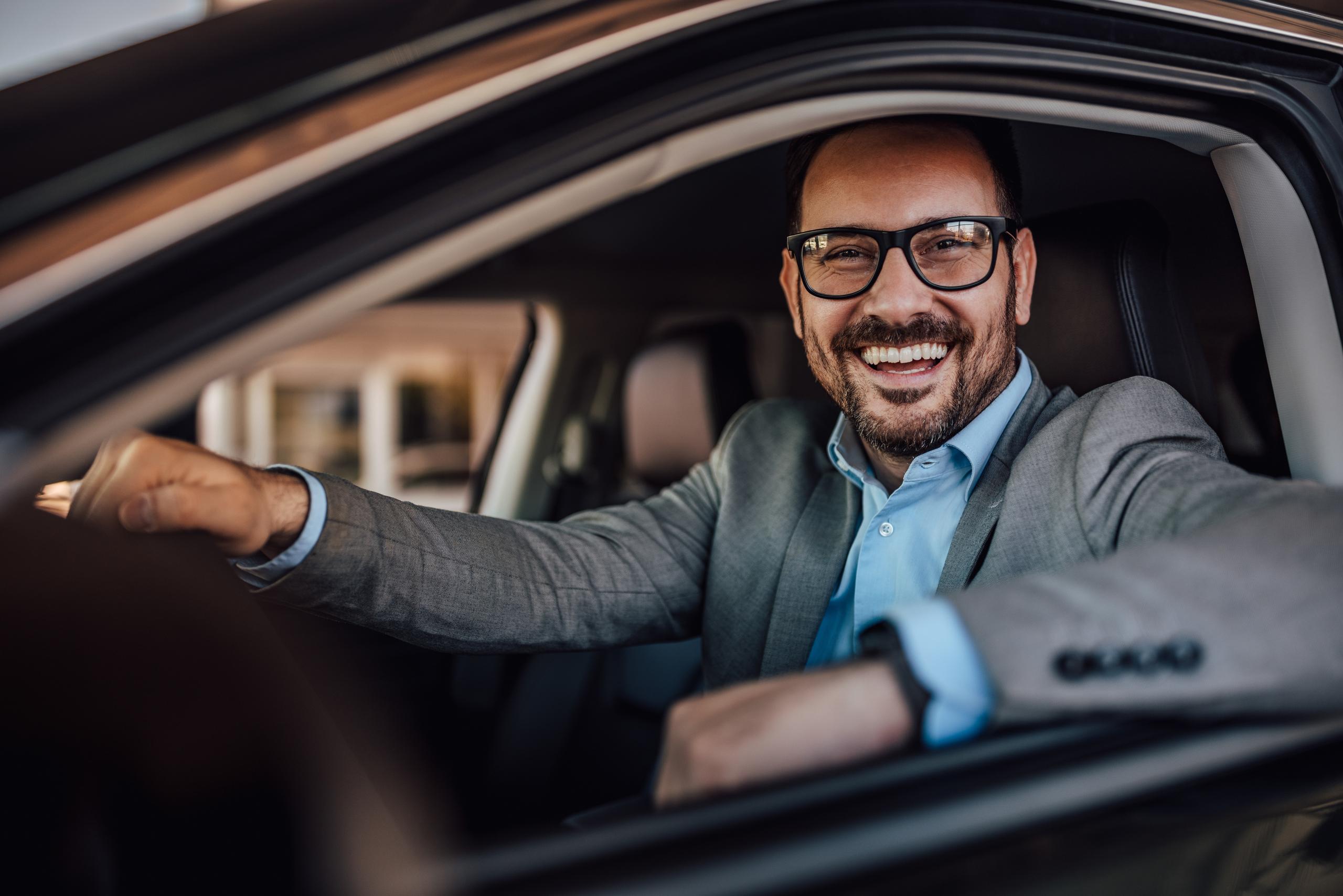 Man smiling looking out car window.