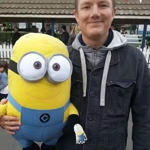 Person holding a Minion character toy at an outdoor family attraction.