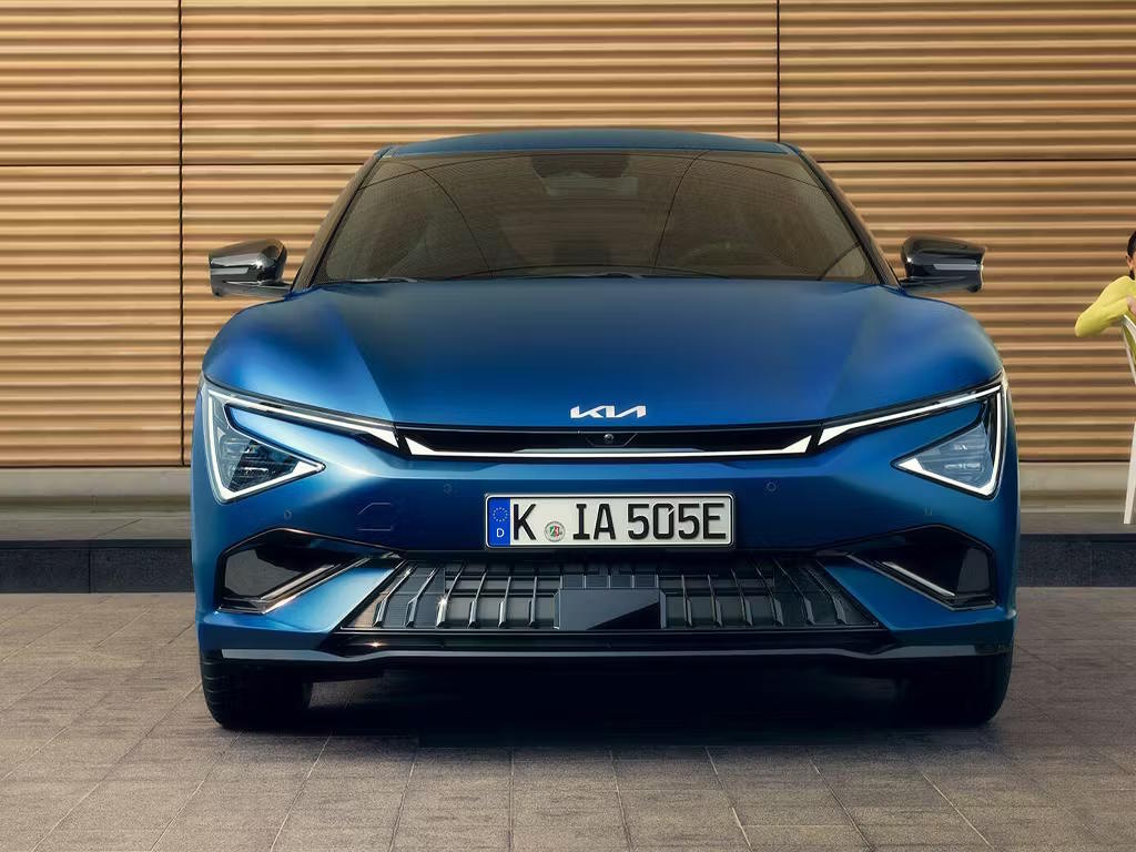 Front view of the Kia EV6 GT in striking blue, featuring the distinctive Tiger Face LED daytime running lights, aggressive lower air intakes and sculpted bonnet design.