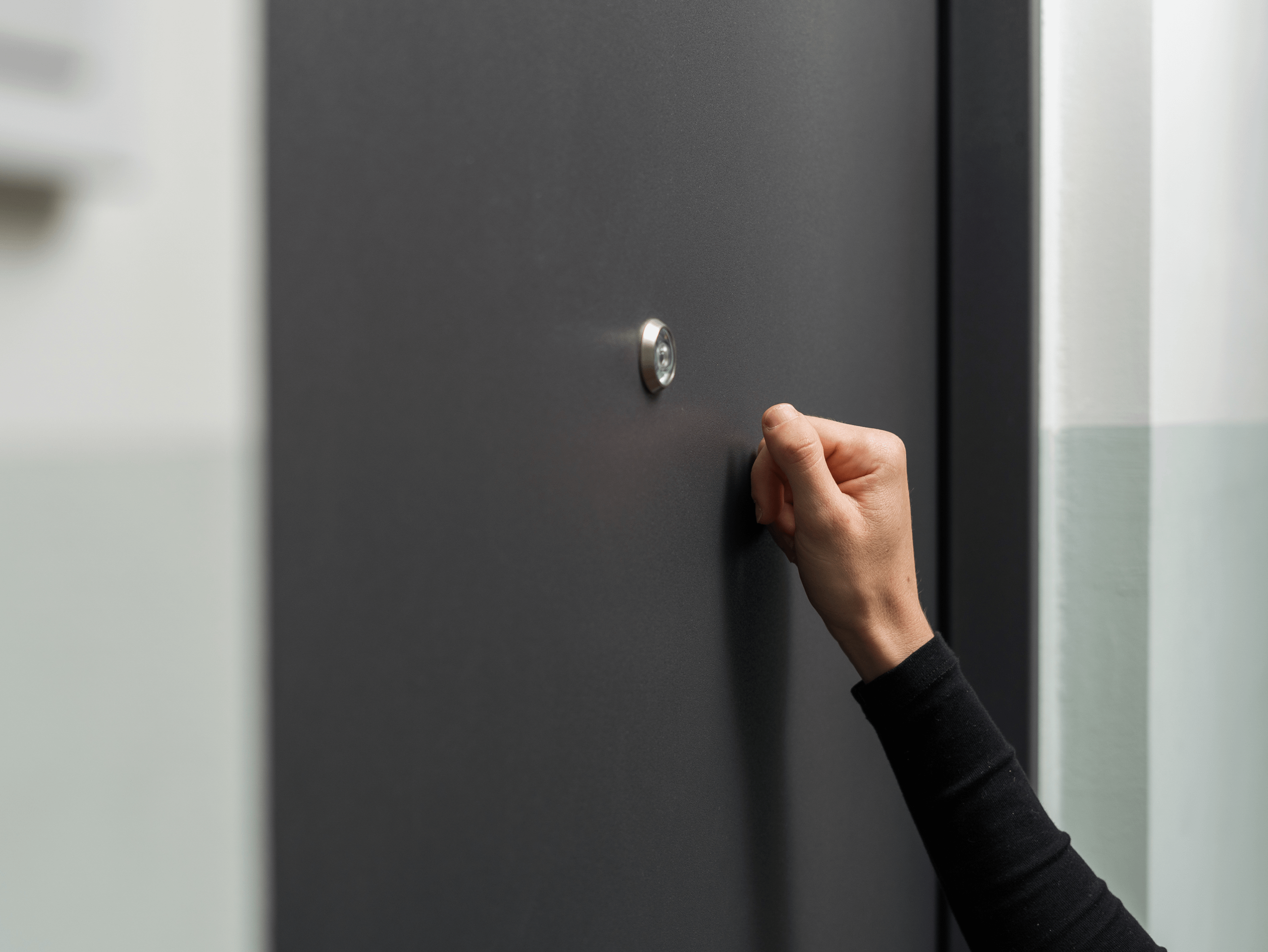 Hand knocking on a black door. 