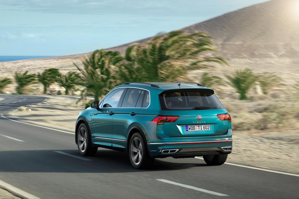 Blue Volkswagen Tiguan driving along desert road with palm trees