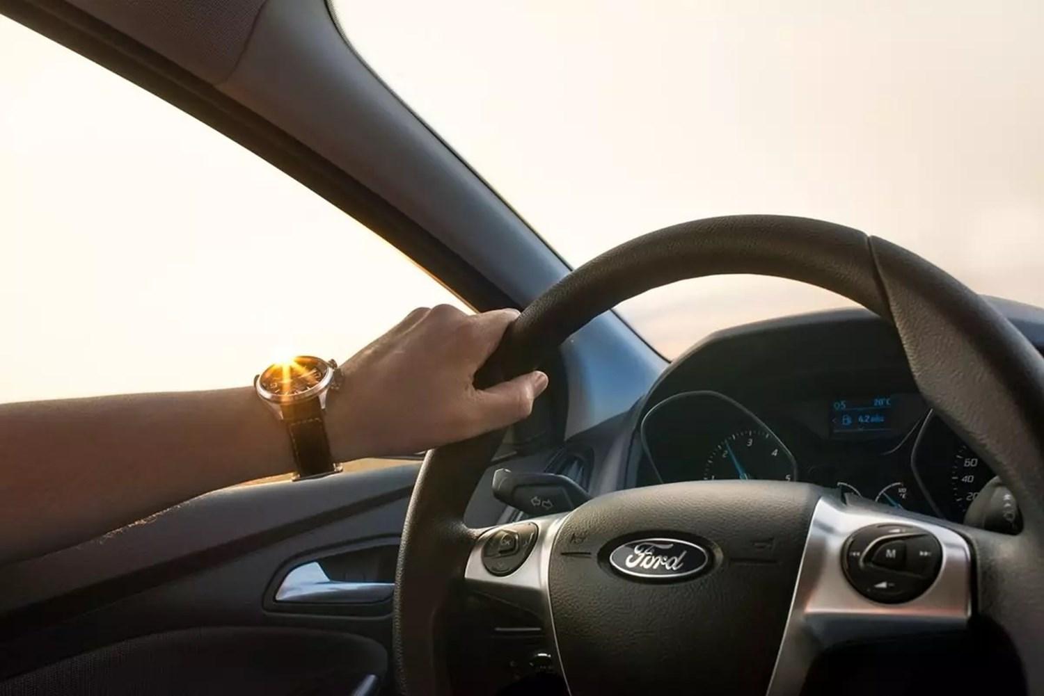 Male hand on Ford car steering wheel 