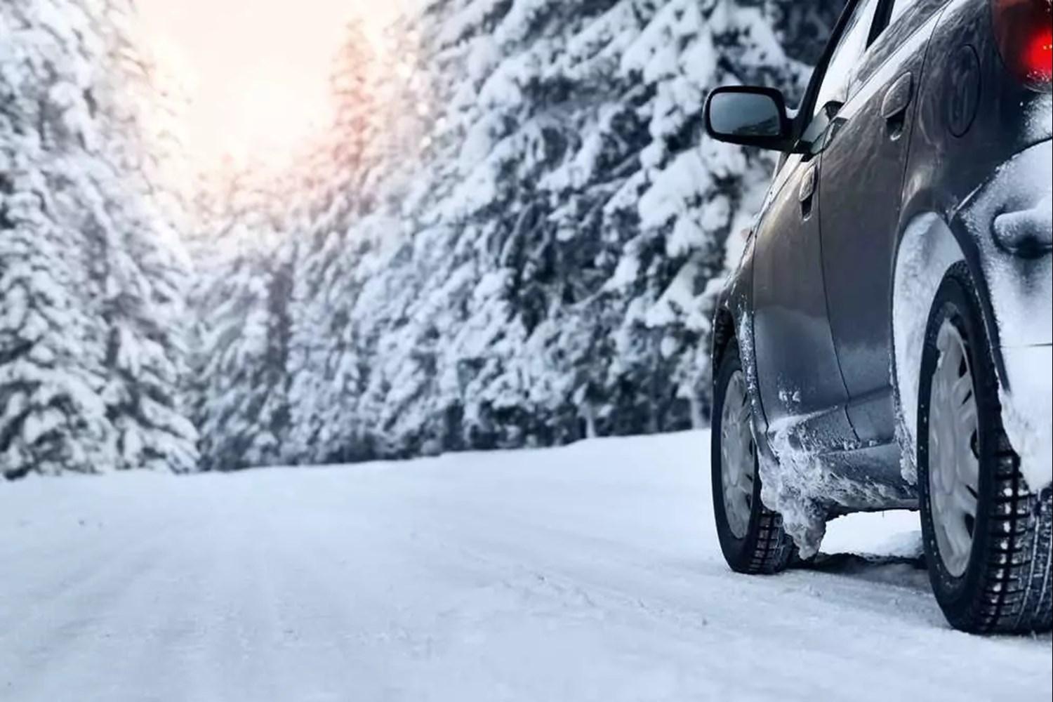 Black car driving up snow covered road - wheel view