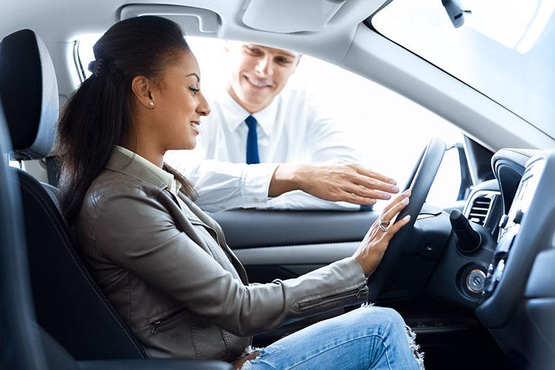 A woman sat in a Ford Motability car with a salesman talking to her about the Ford Motability Scheme