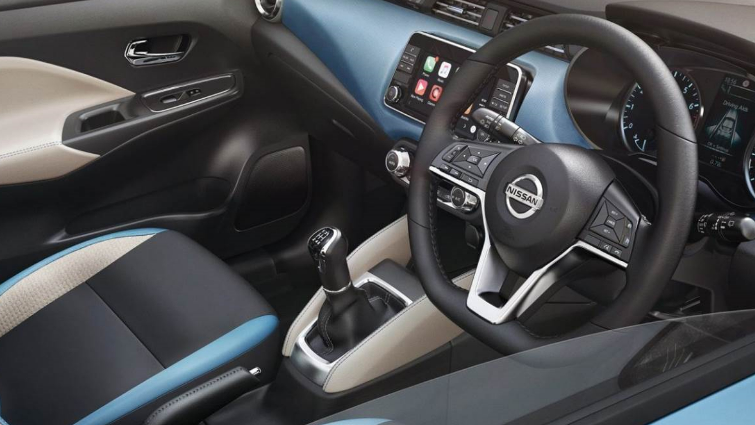Steering wheel with Nissan logo and automatic gear stick inside a new Nissan car in the UK