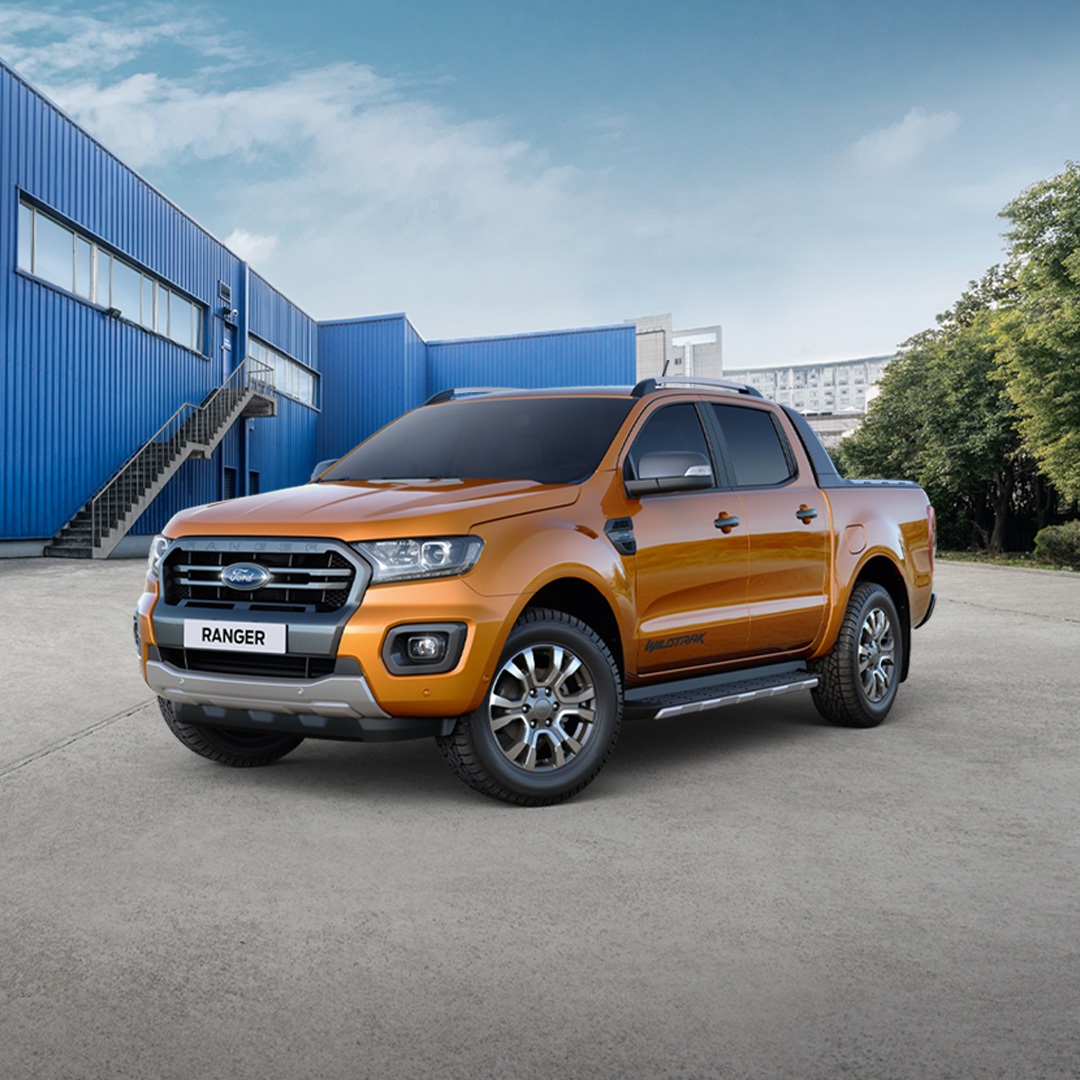 A new Ford Ranger Wildtrak parked outside of a blue building that looks like warehouse.