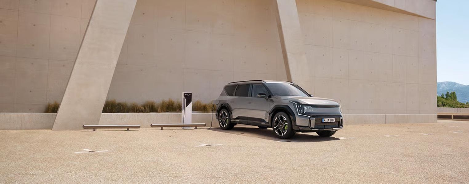 Kia EV9 GT Charging outside a contemporary building.
