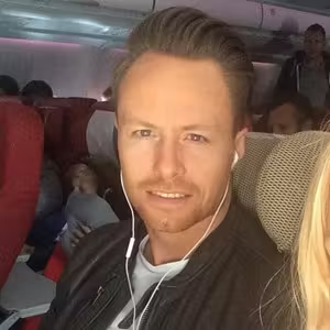 Person sitting in an airplane cabin looking towards the camera while travelling.