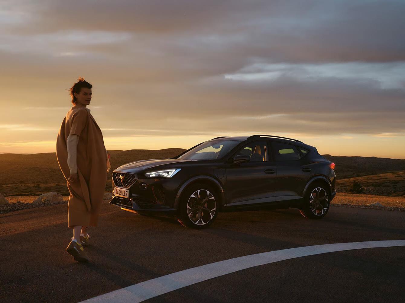 Cupra SUV parked at sunset with a person standing nearby.