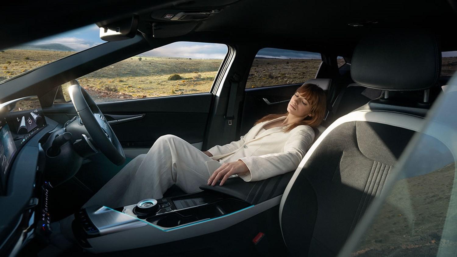 a woman relaxing in Kia EV6's reclining driver's seat