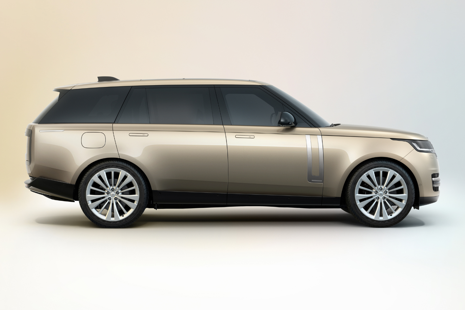 Side profile of gold Range Rover in studio setting.