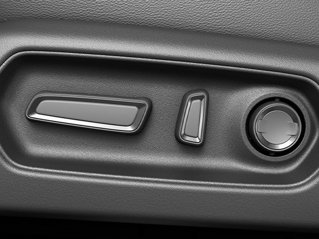 Close-up of the Suzuki e Vitara electric seat adjustment controls, featuring intuitive rocker switches and lumbar support dial finished in dark grey trim.
