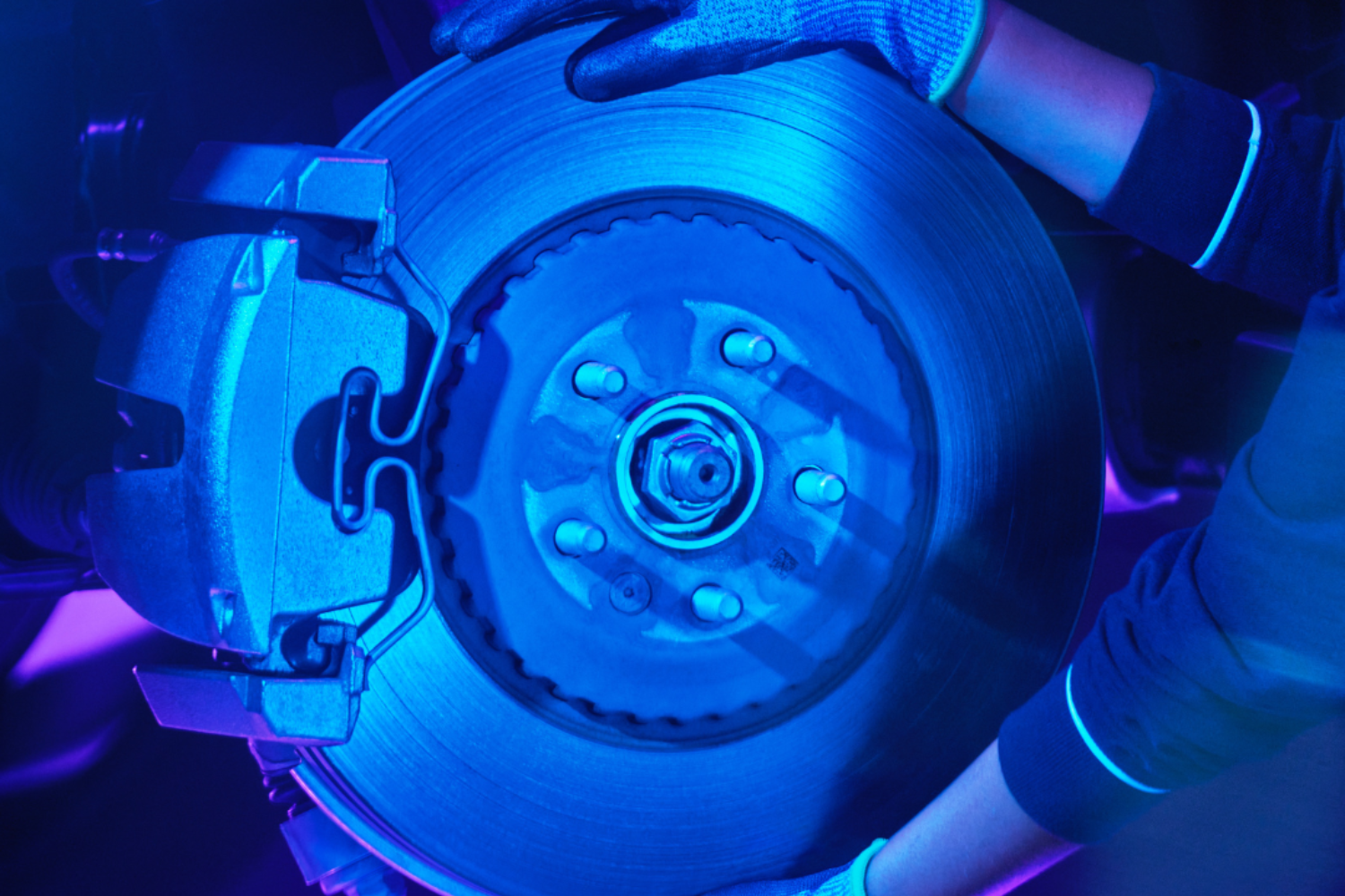 Brake disc and caliper illuminated during professional vehicle maintenance.