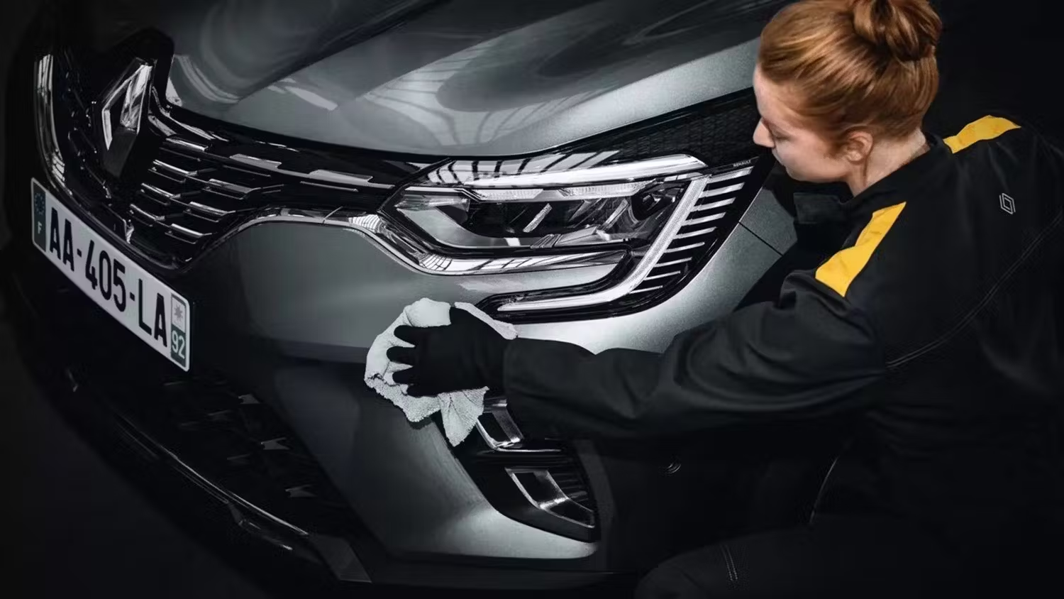 Renault vehicle front detail being cleaned, showing headlight and grille close-up.