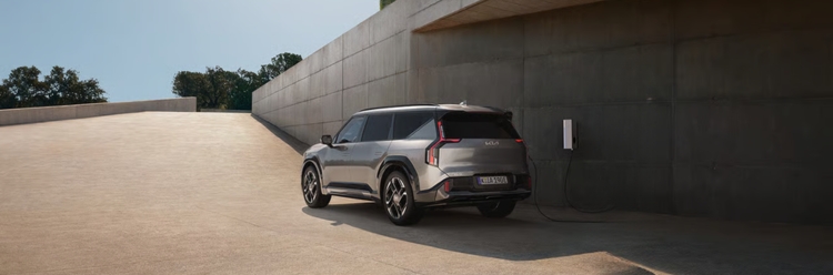 Kia EV9 GT rear view while charging at a modern contemporary building.