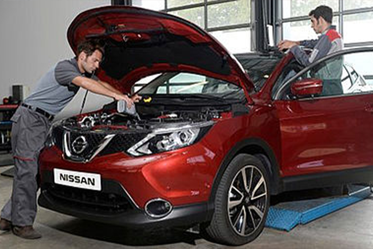 mechanics working on red Nissan