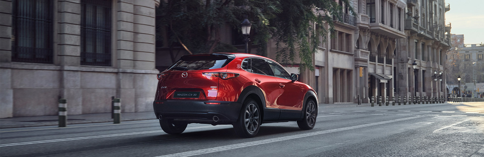 Red mazda cx-30 driving on a city road.