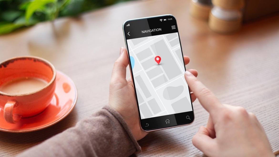 Smartphone showing a navigation map with a location pin beside a cup of coffee.