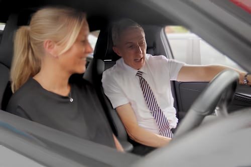 Sales advisor explaining vehicle controls and technology to a customer.