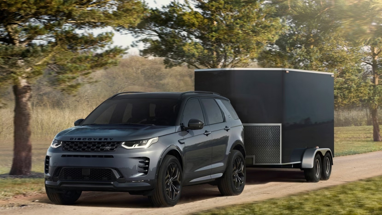 Land Rover Discovery Sport towing a trailer along a countryside road.
