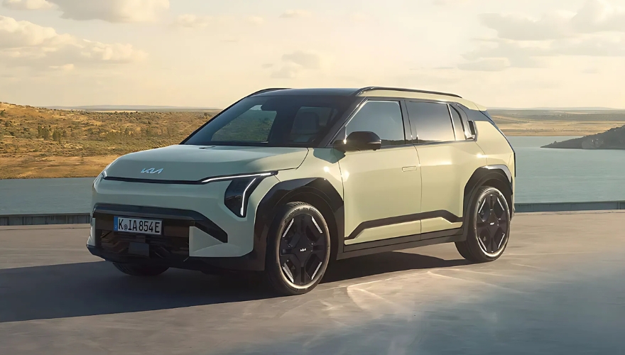 Green Kia EV3 parked beside a scenic lakeside backdrop.