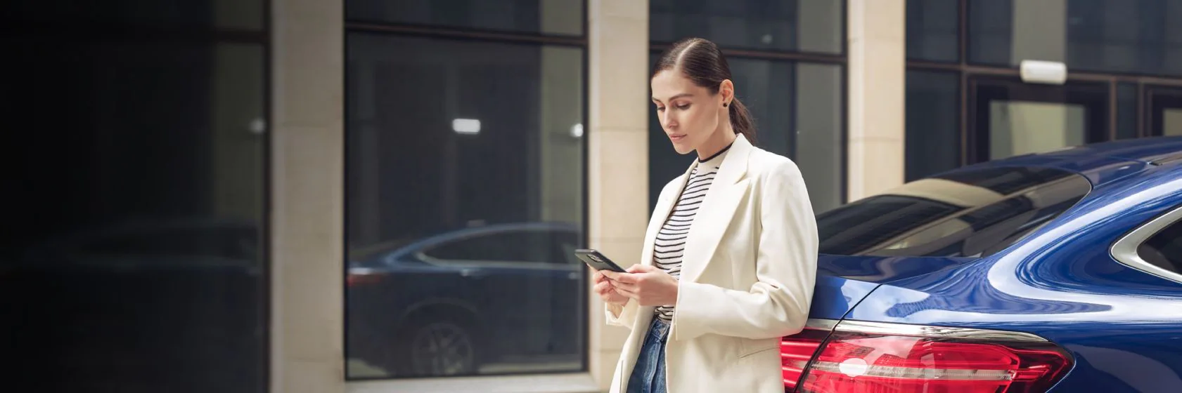 Woman stood in front of Blue Mercedes on phone