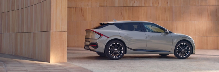 Grey Kia EV6 side exterior view against a contemporary wooden wall.