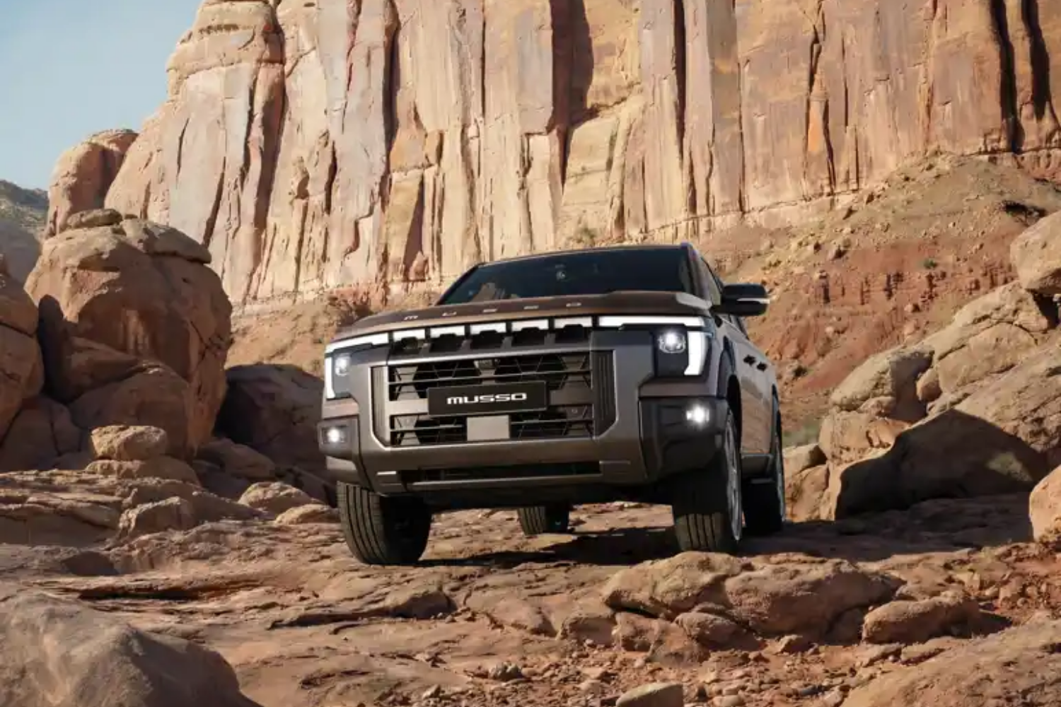 KGM Musso Rhino pickup truck driving through rocky desert terrain