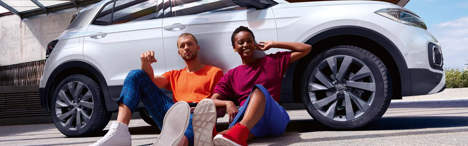 People leaning on Volkswagen vehicle