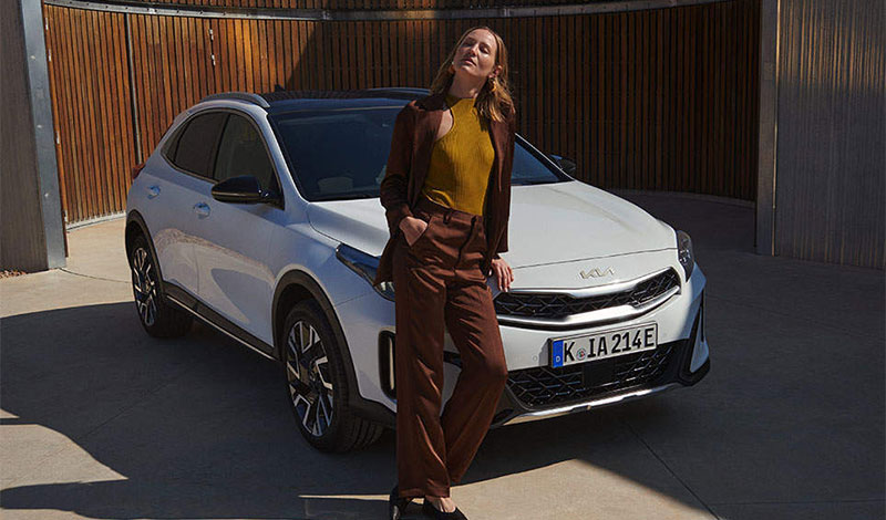 Woman leaning up against a white Kia XCeed