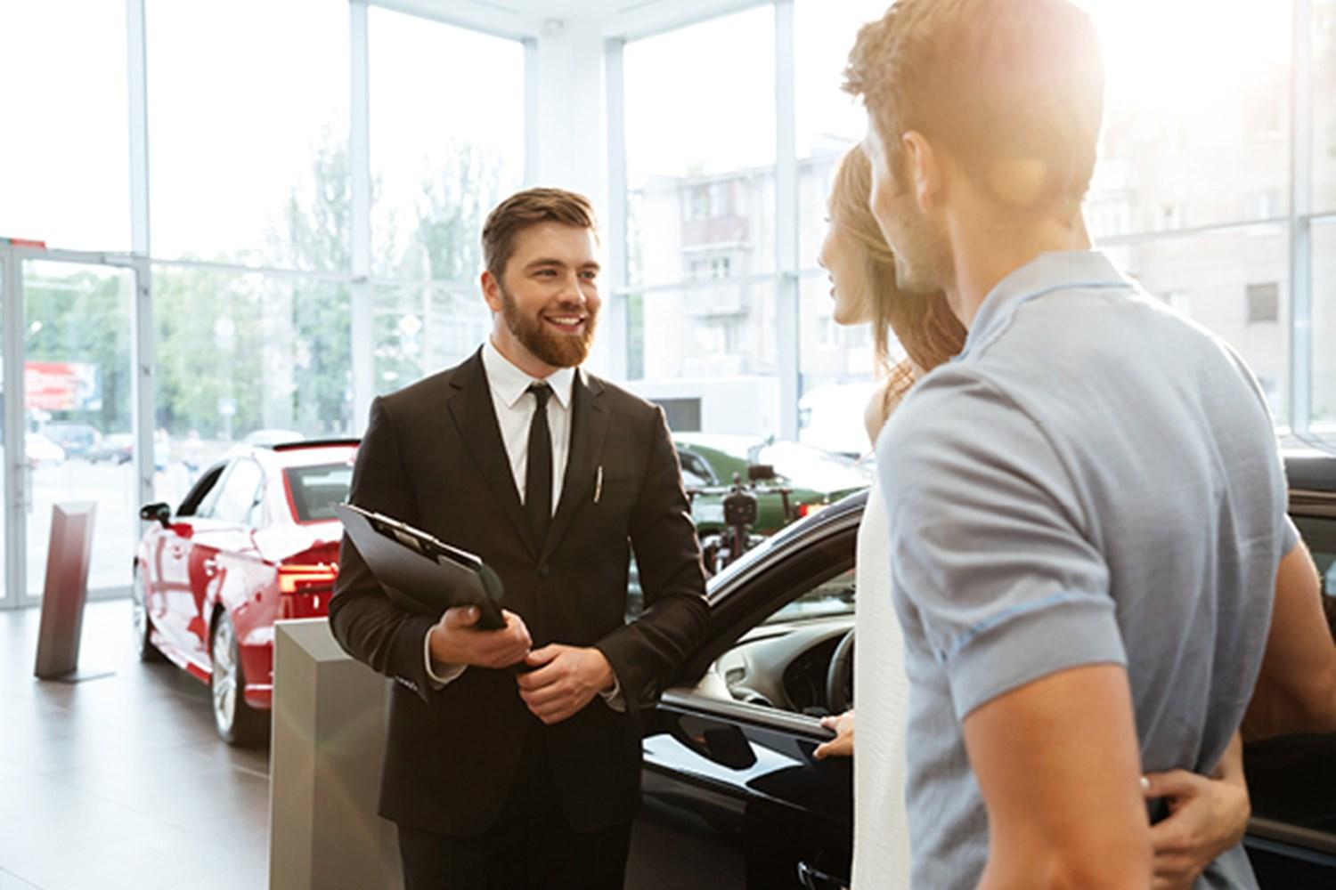 Salesman with couple looking at a car