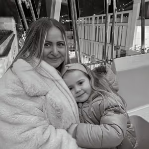 Black and white photograph of an adult and child sharing a hug at an indoor attraction.