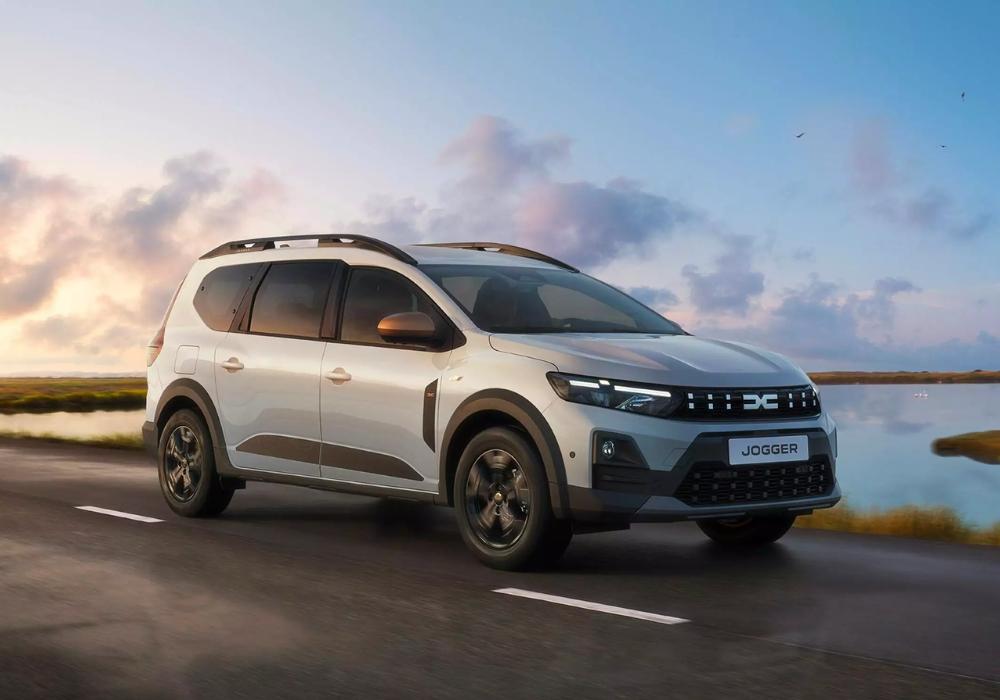 Dacia Jogger driving along a coastal road, showcasing versatile design and family-friendly proportions.