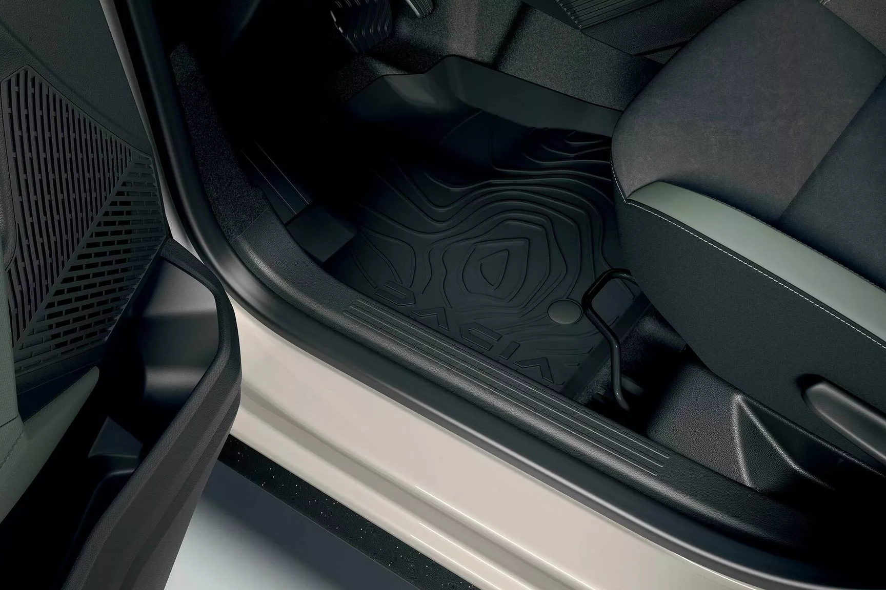 Dacia Duster interior footwell with durable rubber floor mat and front seat visible, highlighting practical cabin design.