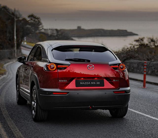 Red mazda mx 30 driving on road