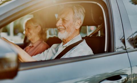 Older man and woman driving car