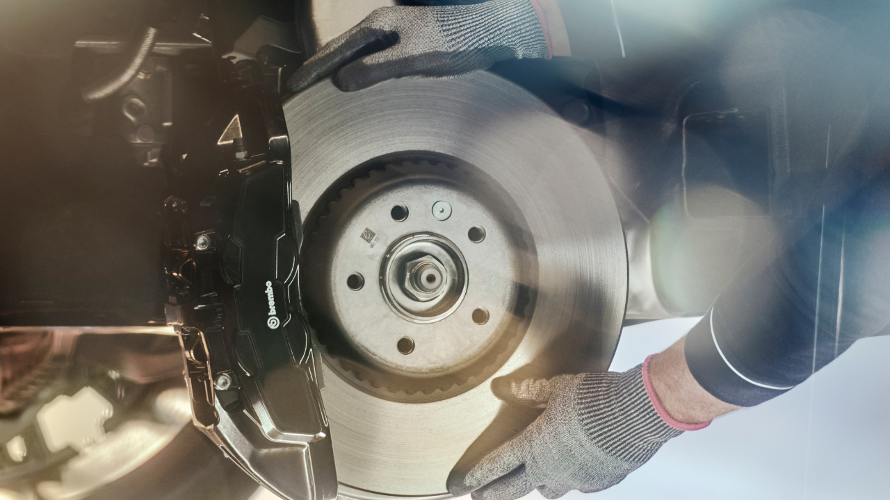 Technician fitting new brake disc and caliper.