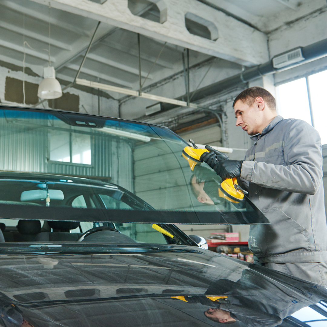 man in grey clothes replacing a car windscreen