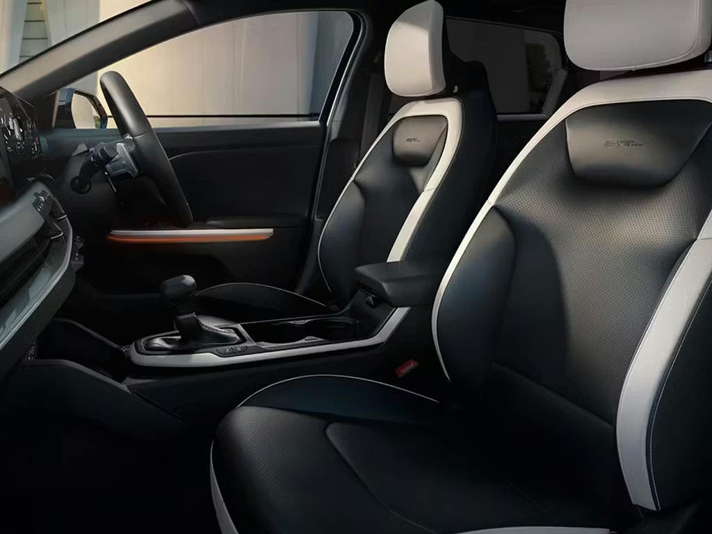 Interior view of the Kia K4 cabin, showcasing the two-tone black and grey sports seats with perforated leather detailing, ambient lighting accents and modern centre console design.