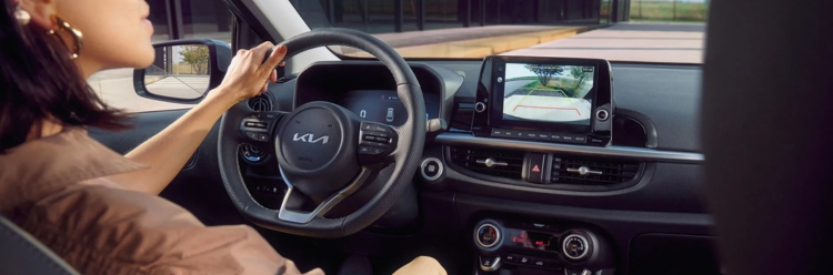 Driver behind the wheel of a Kia Picanto showing the dashboard.