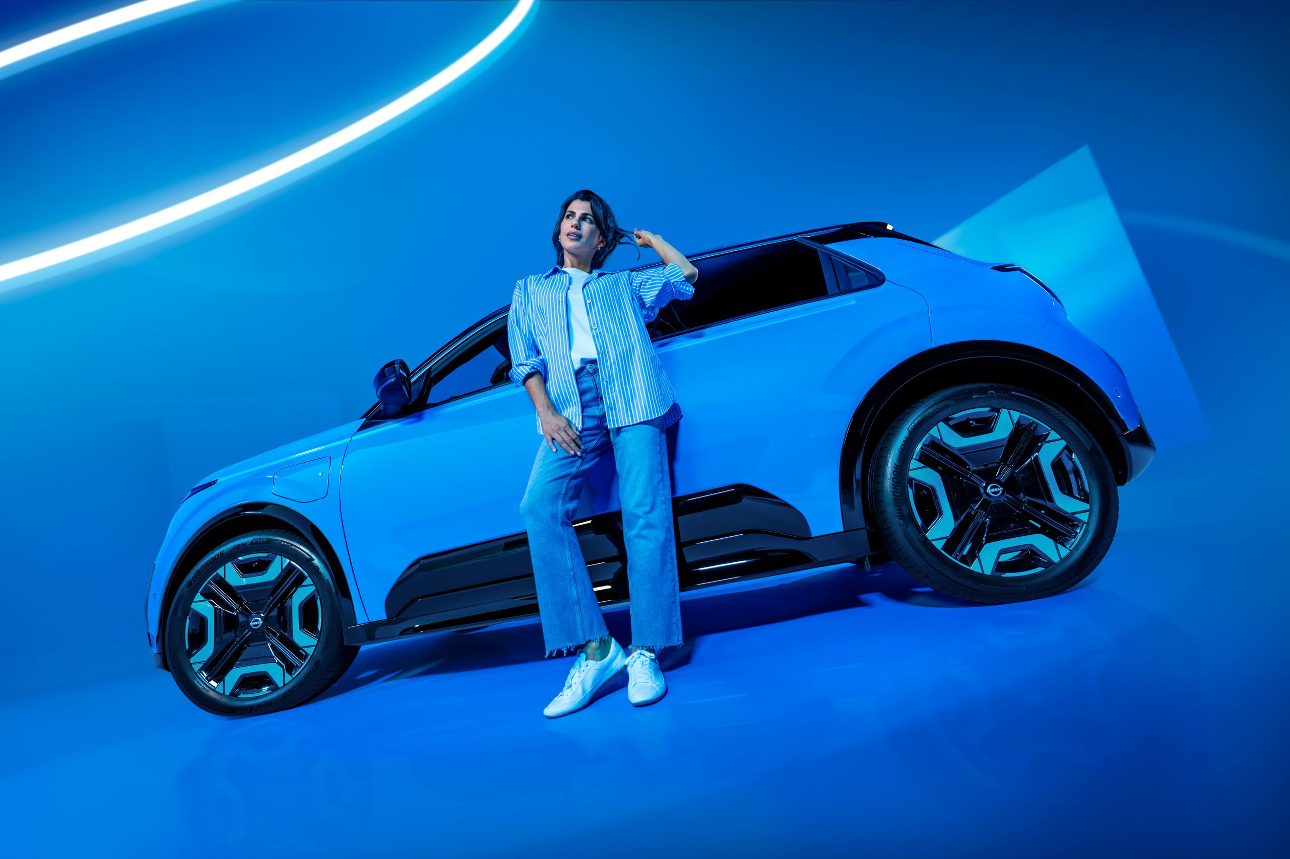 woman dressed in blue leaning against a blue car