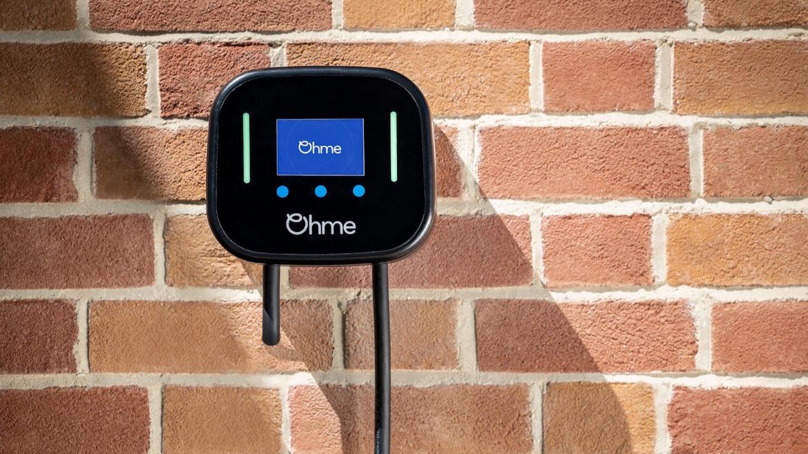 Ohme home EV charger mounted on a brick wall.