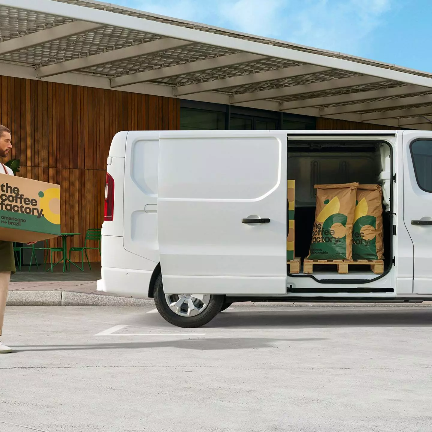 Side exterior view of white Renault Trafic with side door open showing The Coffee Factory sacks in the cargo area.