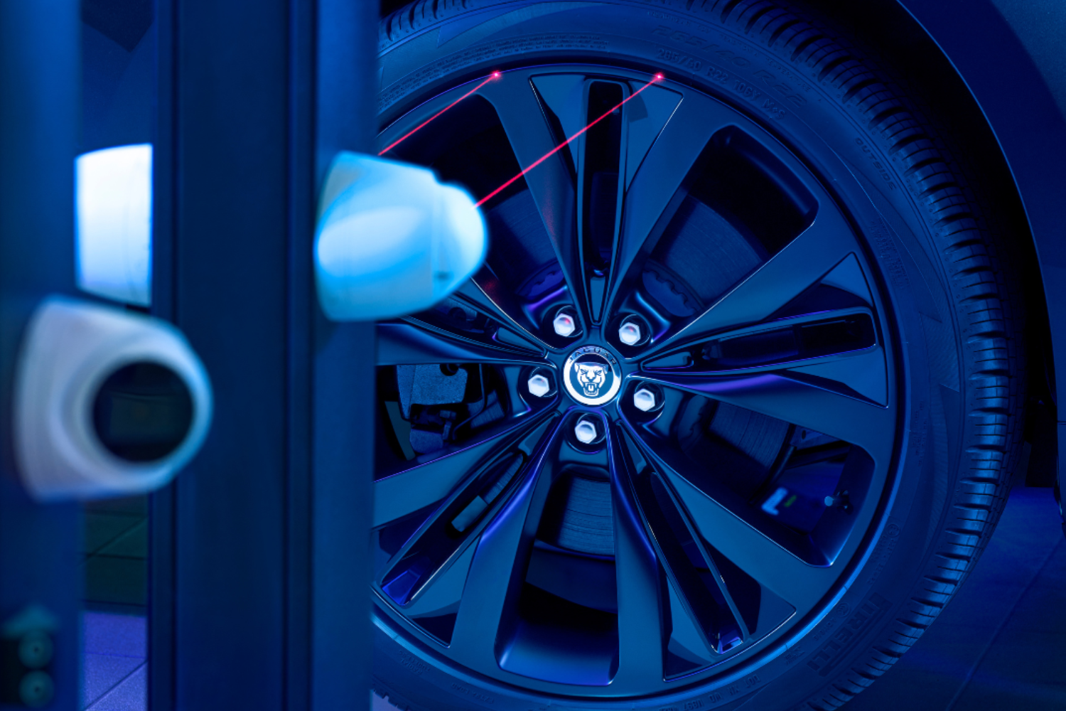 Jaguar alloy wheel undergoing laser wheel alignment in workshop.