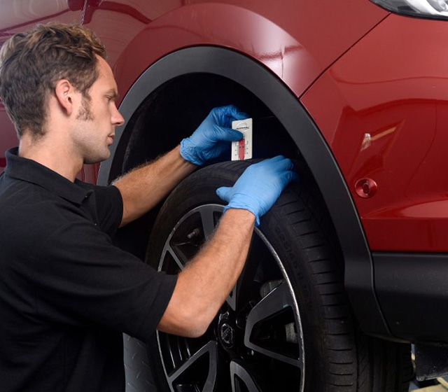 Nissan technician checking the tyre tread depth on a tyre.