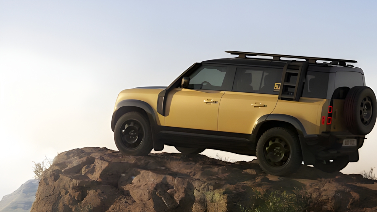 Side profile of the Defender Trophy Edition climbing a rocky hill, showing roof rack and rear ladder.