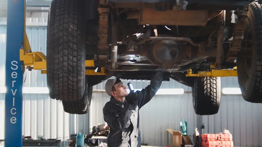 Mechanic working on vehicle from underneath